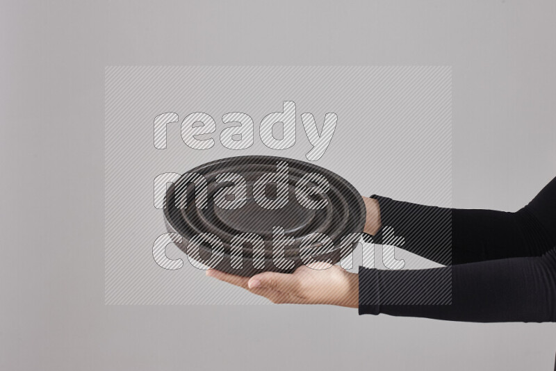 امرأة ترتدي عباءة سوداء تحمل أدوات فخارية مختلفة في أوضاع متعددة