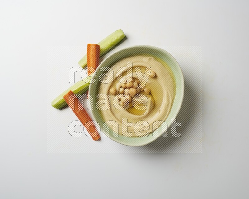 Hummus in a green plate garnished with roasted chickpeas  on a white background