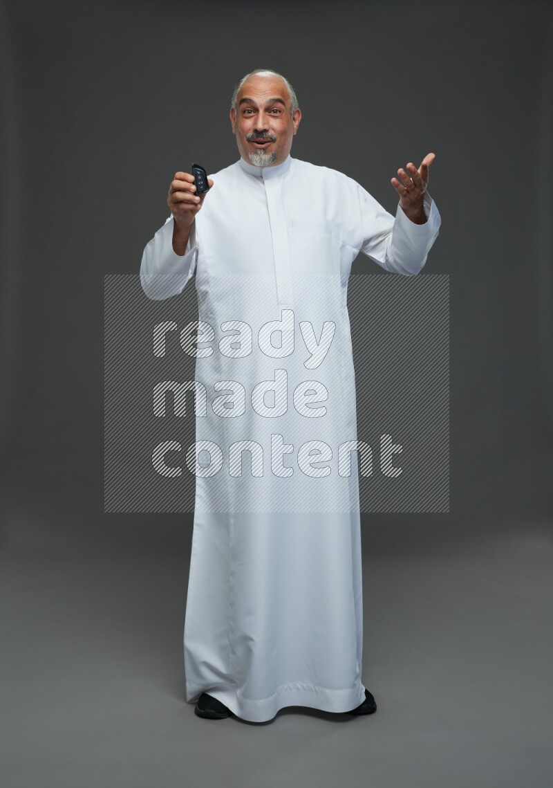 Saudi man without shomag Standing holding car key on gray background