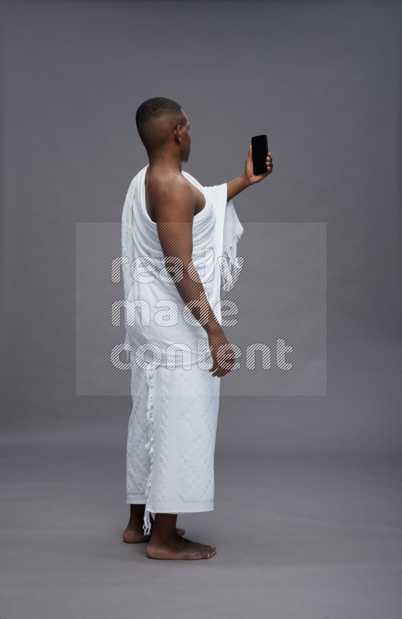 A man wearing Ehram Standing taking selfie on gray background