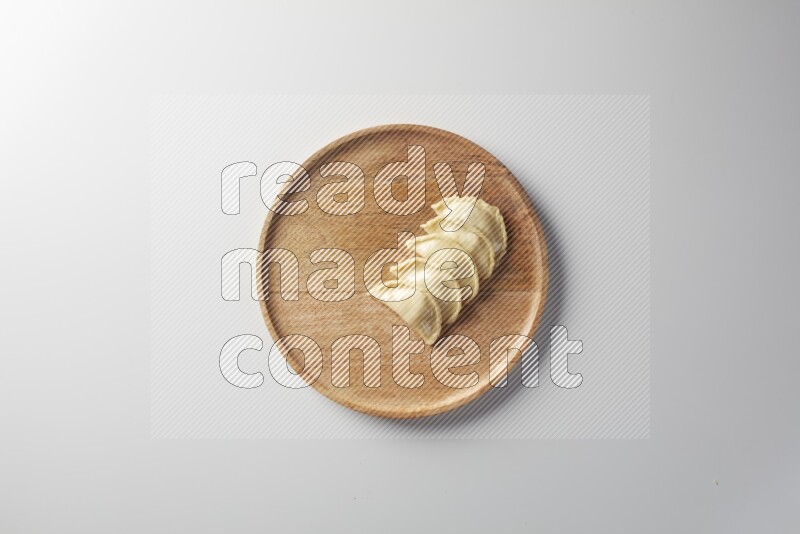 Five Sambosas on a wooden round plate on a white background