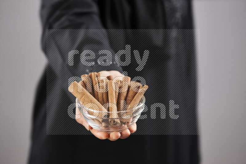 Woman in abaya holding different kinds of spices in different positions
