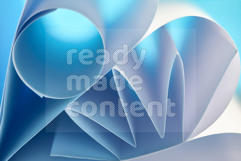 An artistic display of paper folds creating a harmonious blend of geometric shapes, highlighted by soft lighting in blue and white tones