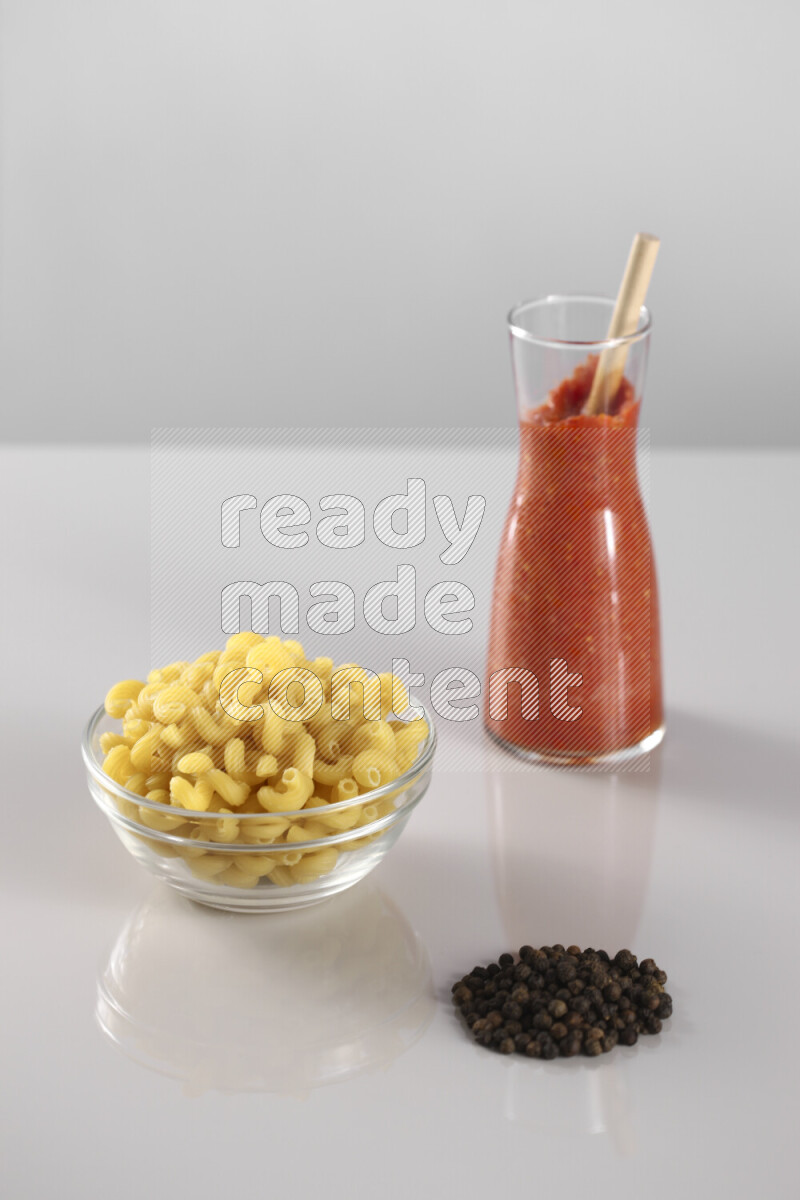 معكرونة مع صلصة طماطم مع مكونات متنوعة من الطماطم والثوم والريحان والفلفل الأحمر والفلفل الأسود والفلفل الأبيض وأوراق الغار والهيل وسنابل القمح على خلفية رمادية