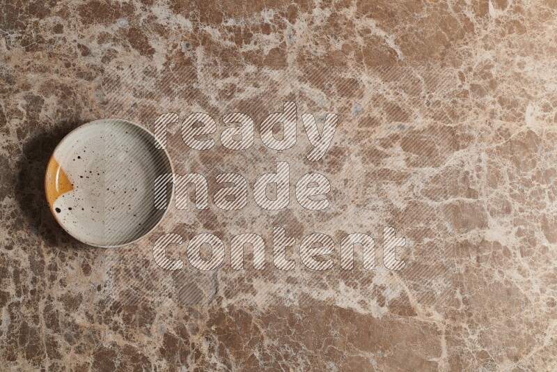 A multicolored pottery bowl on beige marble background