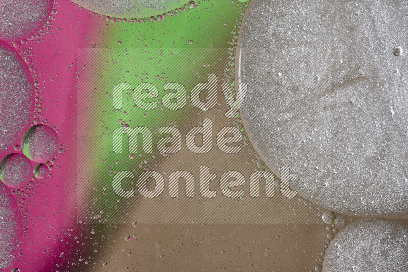 لقطات مقربة لفقاعات من الزيت على سطح الماء باللون البني والأخضر والوردي