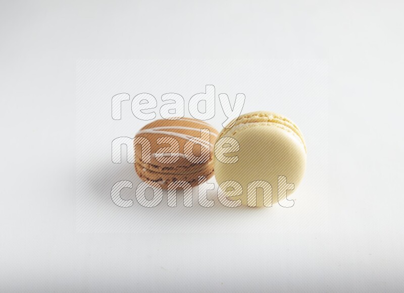 45º Shot of of two assorted Brown Irish Cream, and Yellow Vanilla macarons on white background