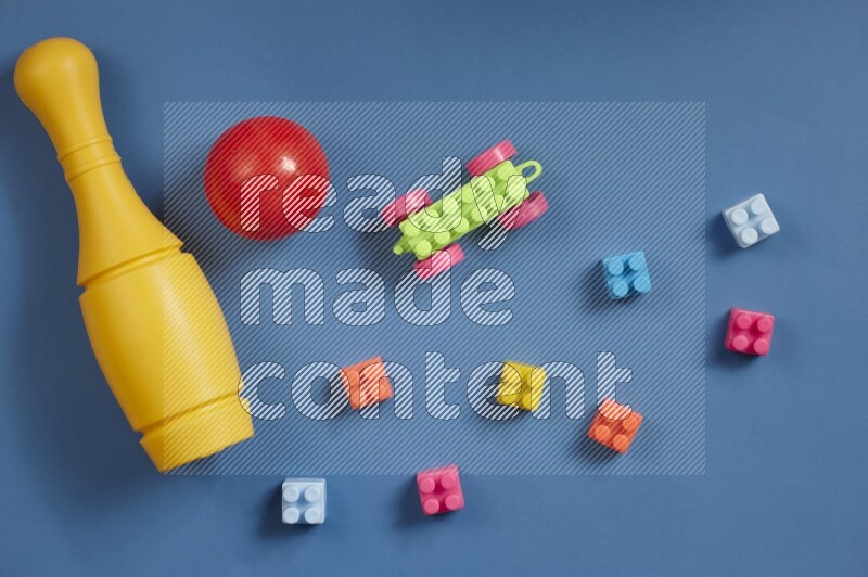 Plastic building blocks, balls and bowling pins on different colored backgrounds (kids toys)