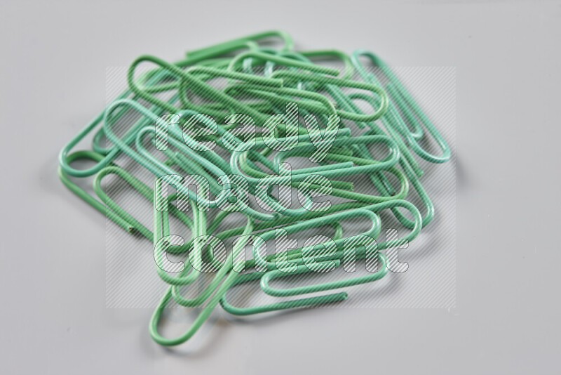 Green paper clips isolated on a grey background