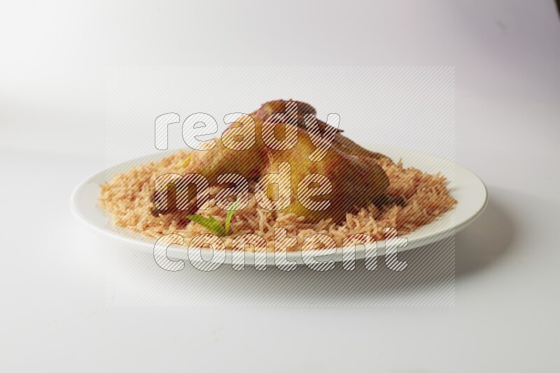 red basmati Rice with kabsa chicken pieces on a white rounded plate direct on white background