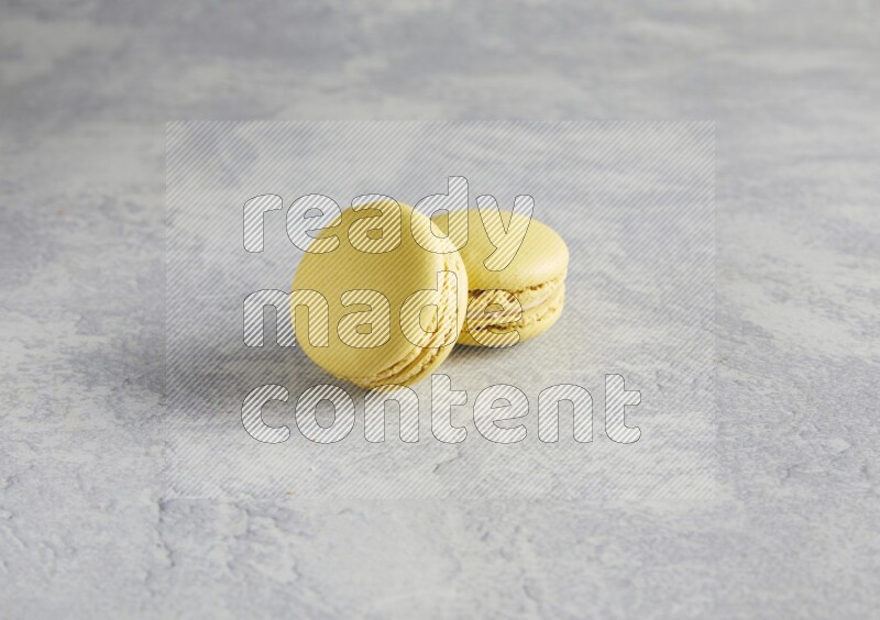 45º Shot of two Yellow Lime macarons  on white  marble background
