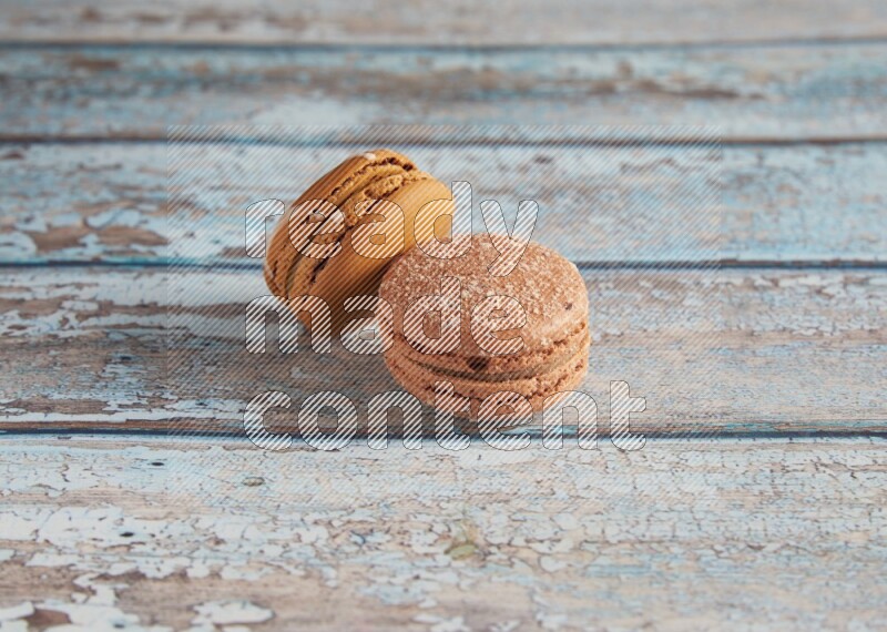 45º Shot of of two assorted Brown Irish Cream, and Brown Hazelnuts macarons  on light blue background