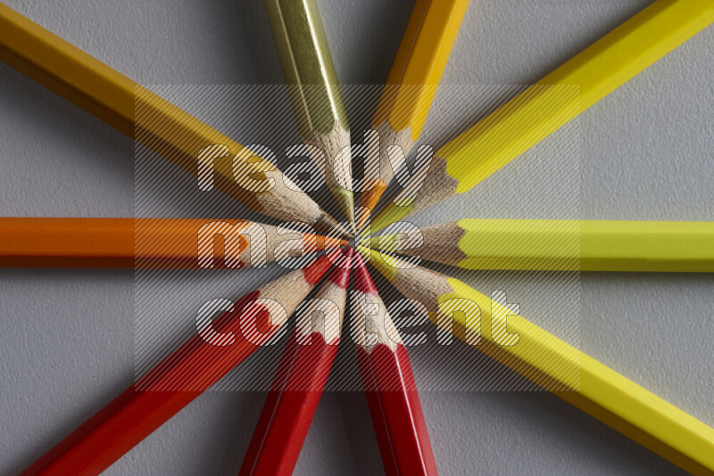 An arrangement of colored pencils in different colors on grey background