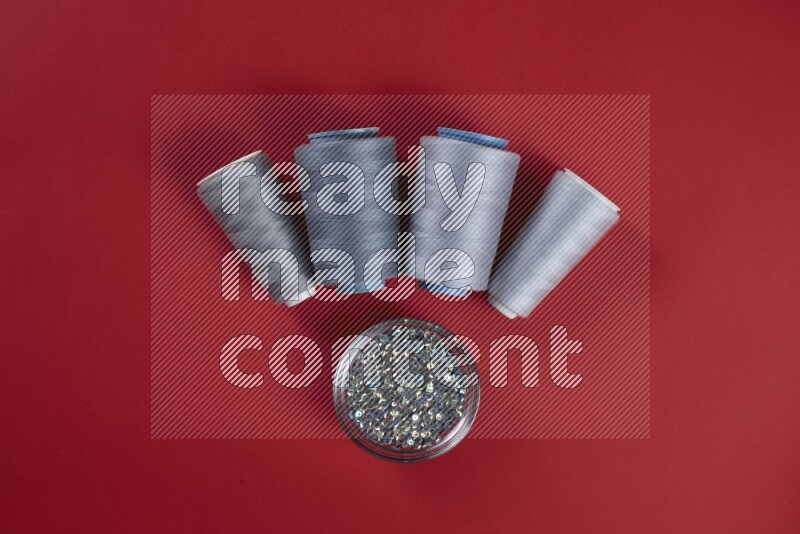 مجموعة من أدوات الخياطة والتفصيل رمادية اللون على خلفية حمراء