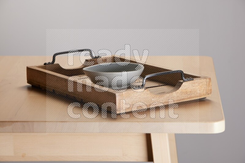 grey bowl on a light colored rectangular wooden tray with handles