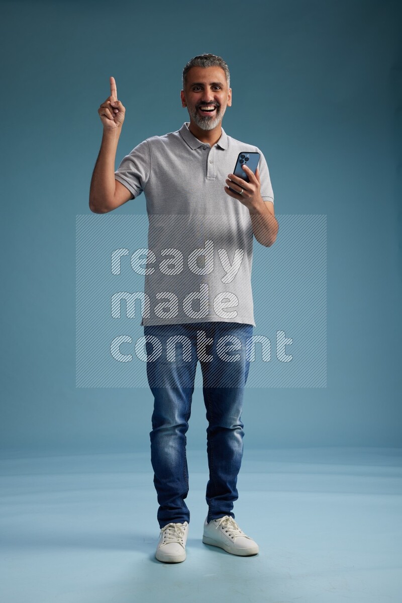 Man Standing texting on phone on blue background