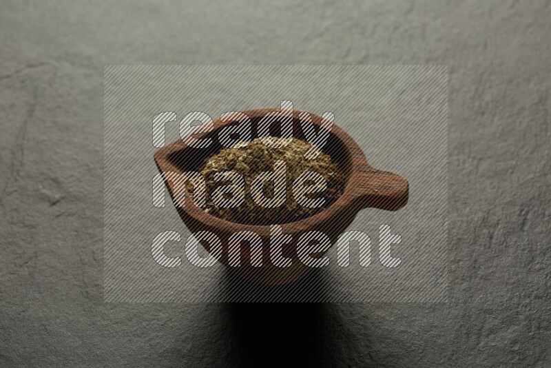 wooden round sauce bowl filled with herbs on grey textured countertop