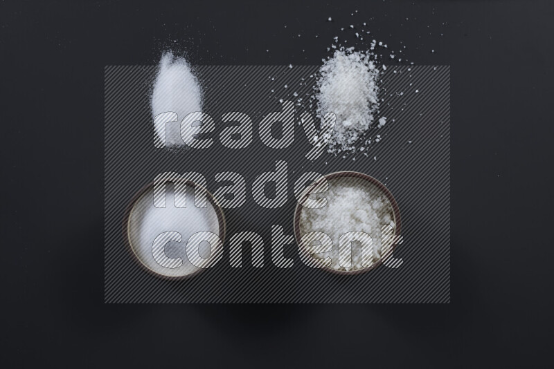 وعاء فخاري ممتلئ بملح الطعام الناعم وملح البحر الخشن على خلفية سوداء