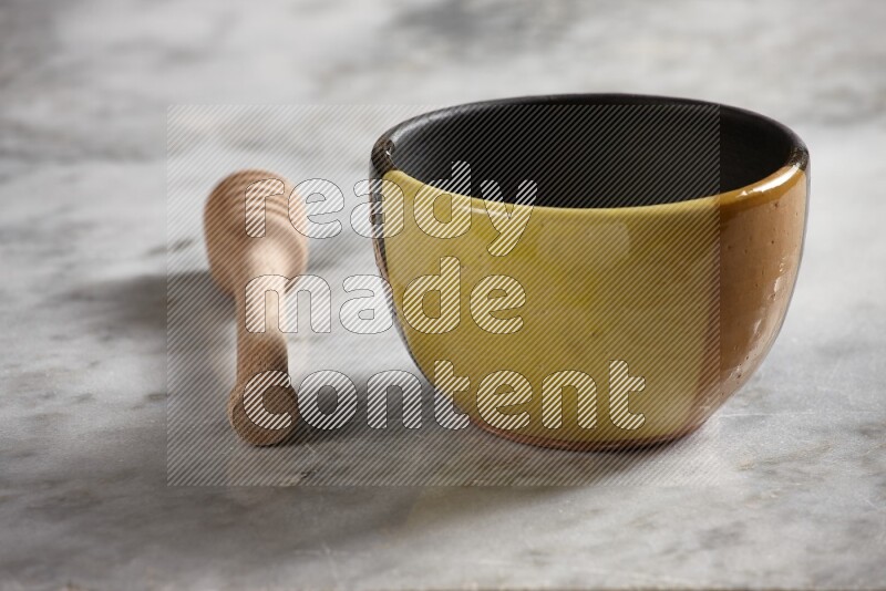 Multicolored pottery bowl with wooden honey dipper on the side on grey marble background