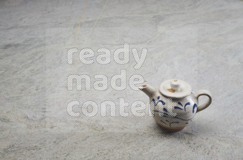 A pottery teapot on grey marble background