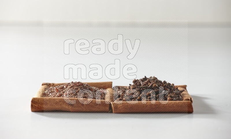 2 squares of cinnamon sticks full of cloves and flaxseeds on white flooring