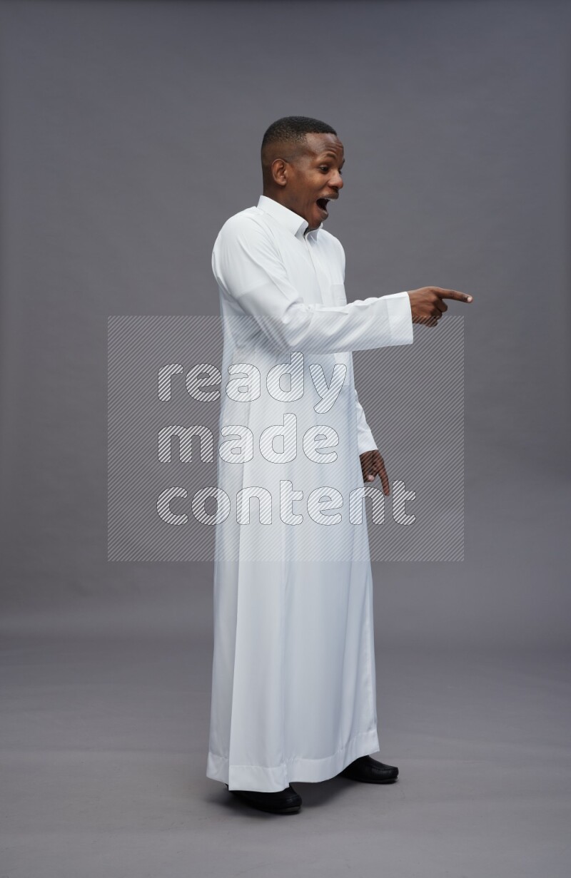 Saudi man wearing thob standing interacting with the camera on gray background