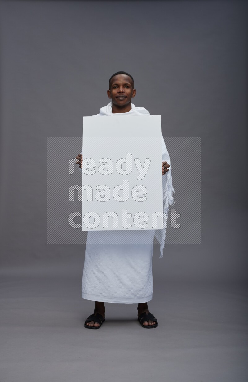 A man wearing Ehram Standing holding board sign on gray background