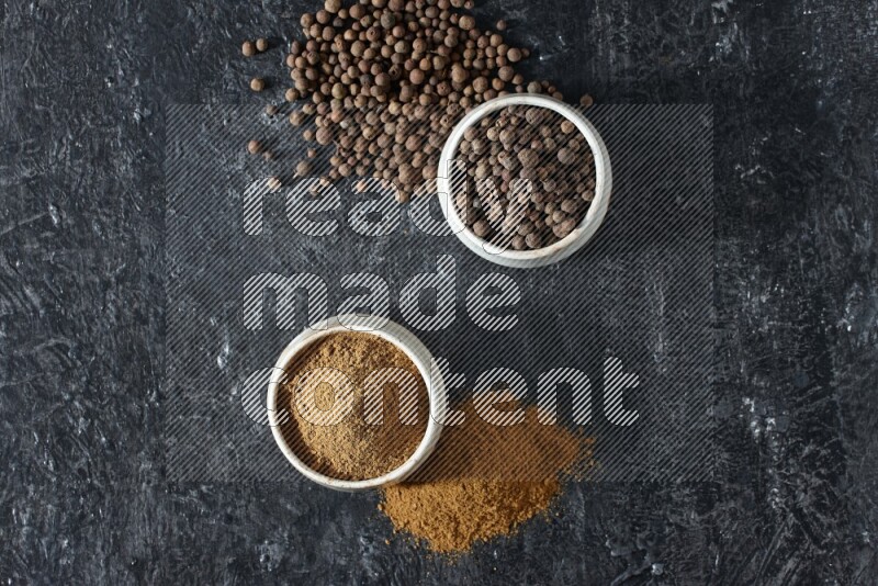 وعاءان بيج، أحدهما ممتلئ ببودرة بهار الفلفل الحلو والآخر بالحبوب وكلاهما متناثران على خلفية سوداء