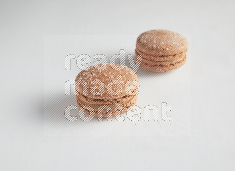 45º Shot of two Brown Hazelnuts macarons on white background