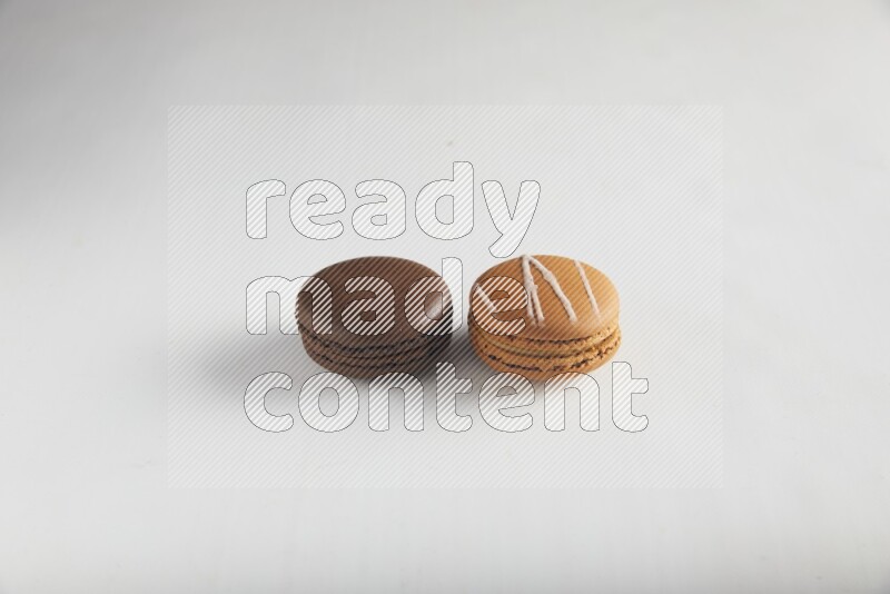 45º Shot of of two assorted Brown Irish Cream, and Brown Dark Chocolate macarons on white background