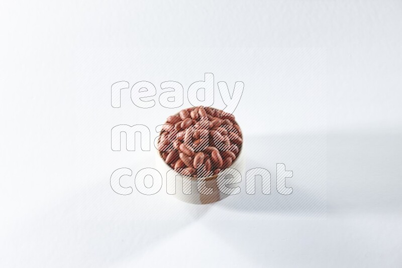 A beige ceramic bowl full of red skin peanuts on a white background in different angles