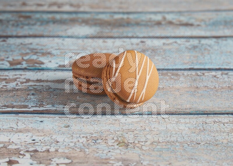45º Shot of of two assorted Brown Irish Cream, and Brown Coffee macarons on light blue background