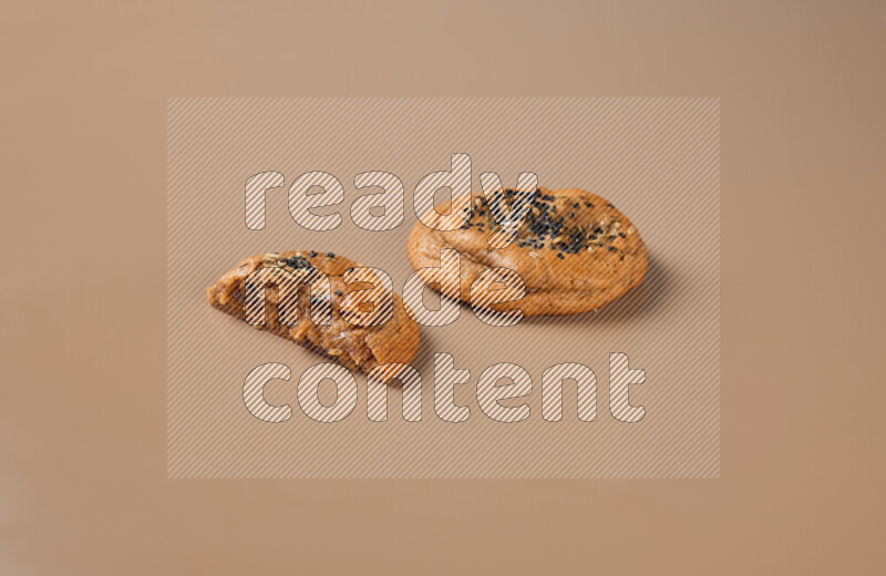a Hasawi cookie field of date and herbs with another one cut in half on a brown background