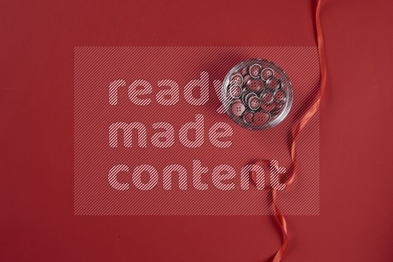 A red collection of sewing and tailoring tools arranged on a red background