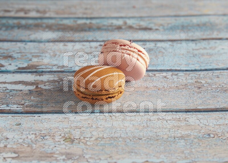 45º Shot of of two assorted Brown Irish Cream, and pink orange blossom  macarons on light blue background