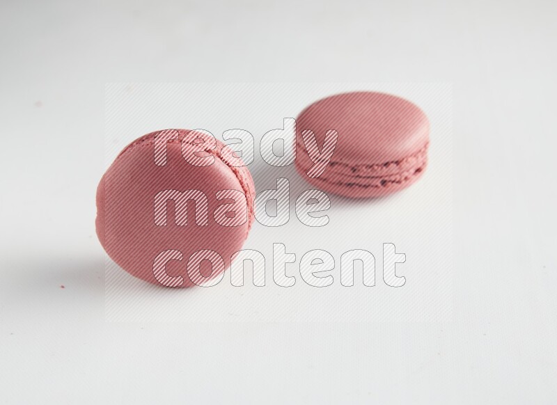 45º Shot of two Pink Raspberry macarons on white background