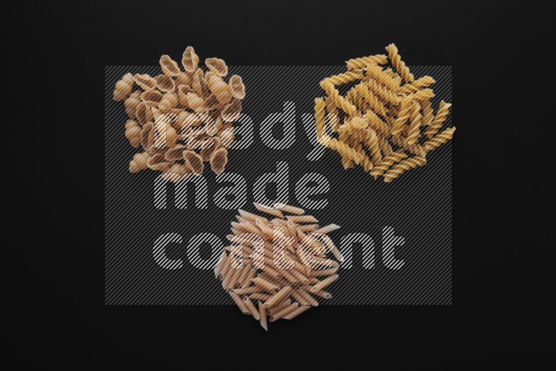 Different pasta types in bunches on black background