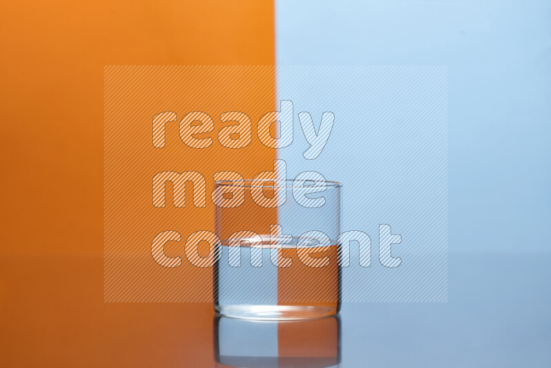 The image features a clear glassware filled with water, set against orange and light blue background