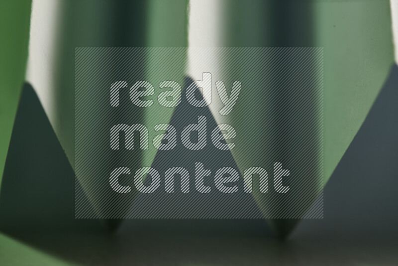 صورة مجردة مقربة تظهر طيات ورقية هندسية حادة بتدرجات اللون الأخضر