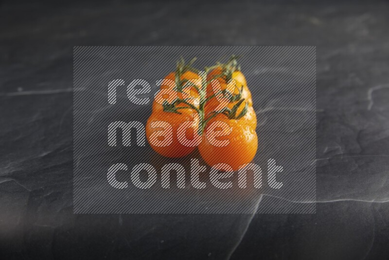 Orange cherry tomato vein on a textured black slate background 45 degree