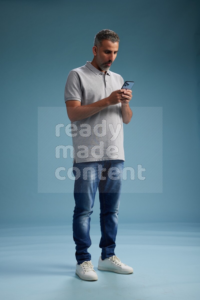 Man Standing texting on phone on blue background
