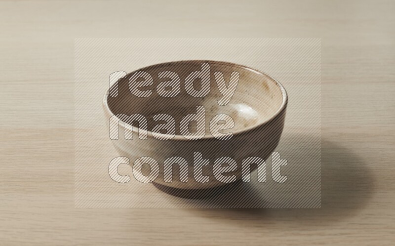 A beige pottery bowl on light wooden background