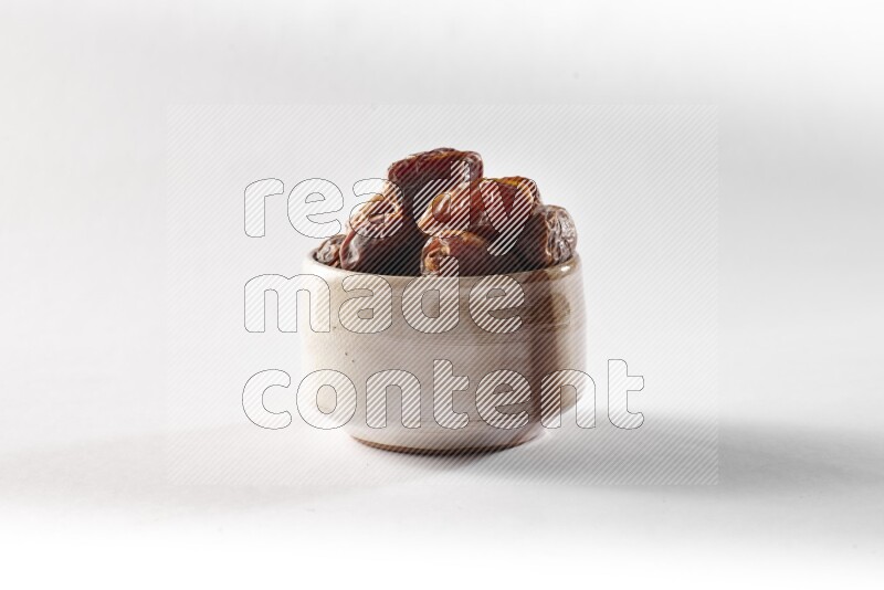 Dates in a beige pottery bowl on white background