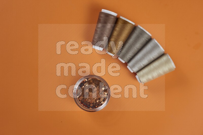 A brown collection of sewing and tailoring tools arranged on a orange background