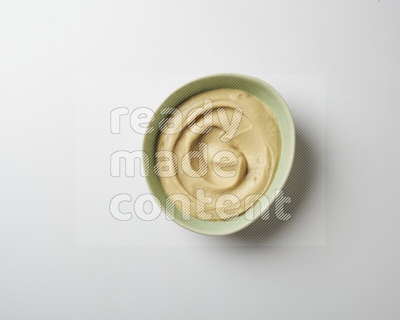 plain Hummus in a green plate on a white background