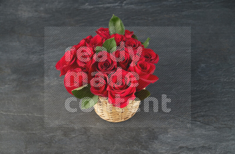 Vibrant red roses in a wicker basket on black marble background