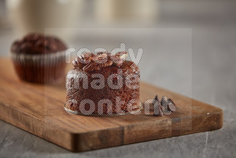 Chocolate cupcake topped with pecan on a wooden board