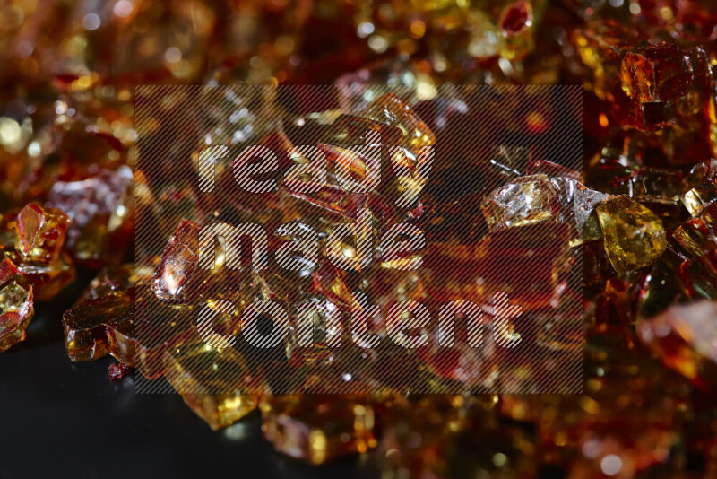 Transparent orange fragments of glass scattered on a black background