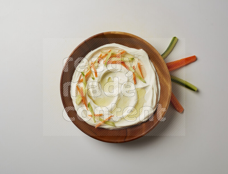 Lebnah garnished with sliced carrots & cucumber in a wooden plate on a white background