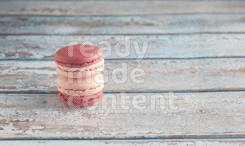 45º Shot of two Pink Litchi Raspberry macarons on light blue wooden background